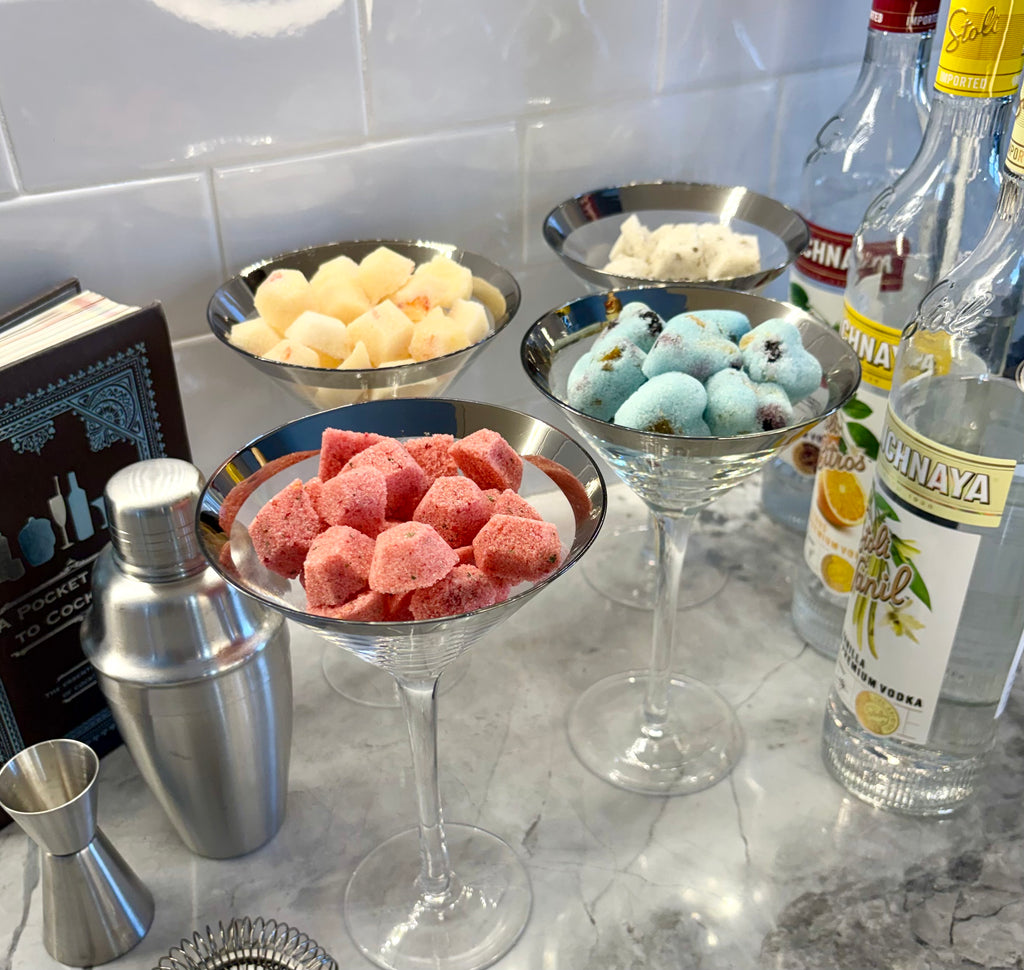 martini glasses full of botanical sweetener cocktail gems on a counter with bottles and a cocktail shaker.